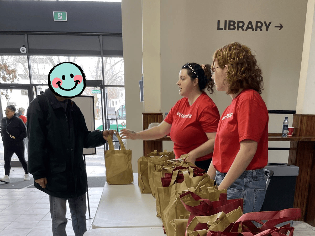 Two volunteers handing out a care pack bag to a community member